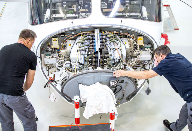 two mechanics working on the engine of helicopter HeliService